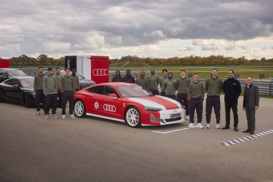Andreas Henke (Vice President Brand Audi), Marco Schubert (Vorstand für Vertrieb und Marketing, AUDI AG), Kapitän Manuel Neuer (v.r.) und die Mannschaft des FC Bayern München stehen um den Audi RS e-tron GT performance, foliert speziell für den FCB