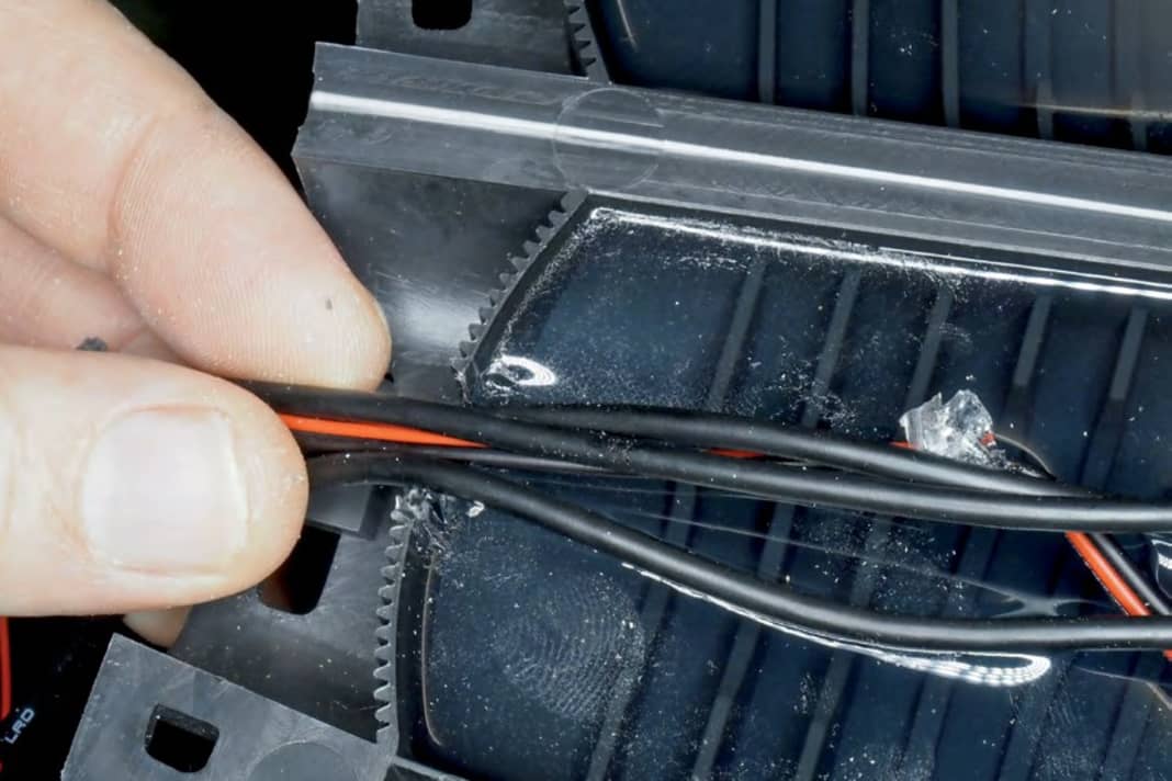 Leitungen an einer Seite heraus führen; Steg in diesem Bereich umlegen, damit die Leitungen nicht scheuern