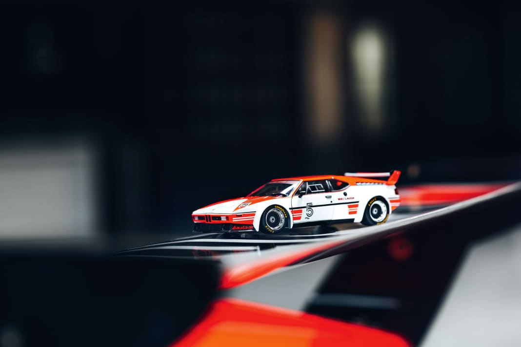 Auf dem Heckflügel des Originals aus der Sammlung Loh verschmilzt das 1:18-Modell des BMW beinahe mit Laudas BMW M1 im Procar-Trimm