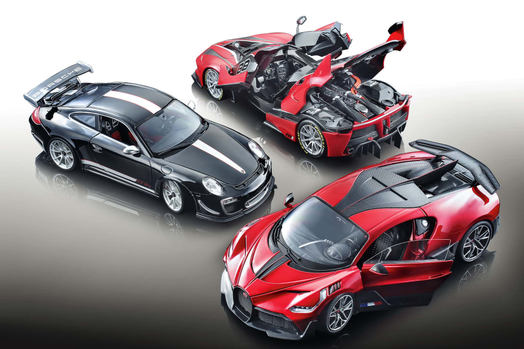 Der Porsche 911 GT3 RS (2011) strahlt in tiefem Schwarz, die 1:18- Modelle des Ferrari FXX K und Bugatti Divo in Rot-Tönen