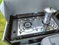 Auf dem linken Auszug thront der Zwei-Flammen- Gaskartuschenkocher, der Windschutz aus Aluminium hat einen eigenen Aufsteller und ist richtig stabil