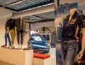 Herzstück der Büroräume von Corporate Fashion Industries ist der Porsche 911 in Agablau. Hinter ihm hängen Muster von Teamjacken, die Schaufensterpuppen tragen ebenfalls Vorführstücke. Rechts im Bild parkt der Taycan Turbo, in der Scheibe spiegeln sich zwei gelbe Elfer aus dem Erdgeschoss wider.
