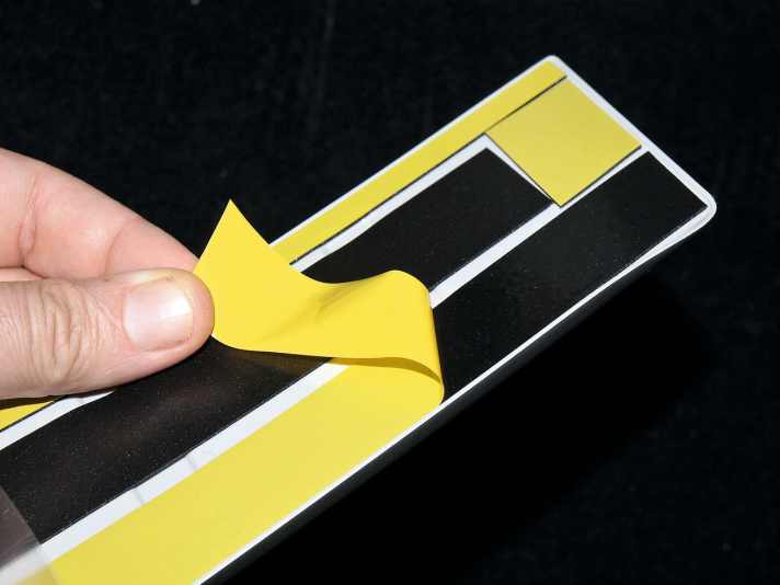   03.
 	Schutzfolie an den Enden ein wenig abziehen, Ladekantenschutz andrücken, Folie ganz herausziehen