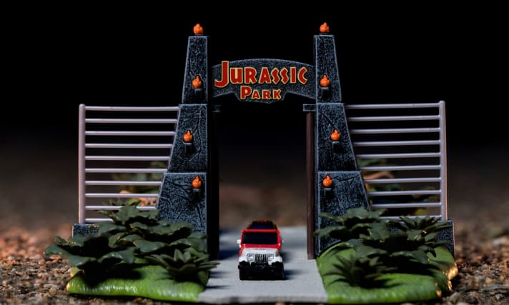 Dank der dramatischen Beleuchtung auf diesem Foto, scheinen dem weiß-roten Jeep CJ7 beinahe die Reifen zu schlottern, als er in das Gelände des “Jurassic Park” hineinrollt]Foto: Werk
