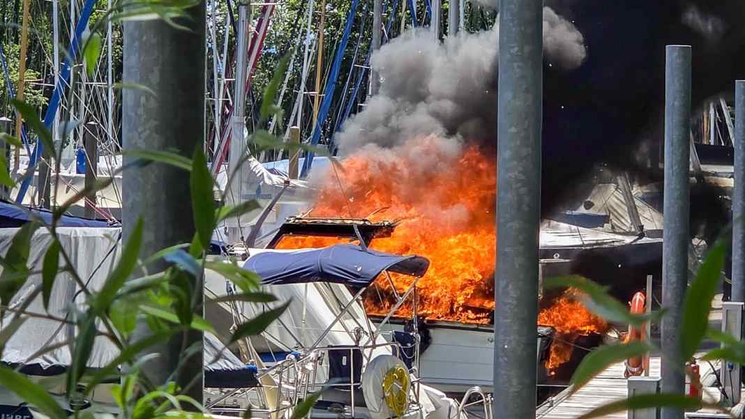 Boot brennt im Yachthafen neben Segelyachten aus