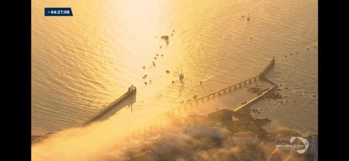   Ein Bild vom Morgen des Starts in Les Sables-d'Olonne, das einerseits die goldene Aufbruchstimmung, andererseits aber auch die etwas gespenstische Leere dort zeigt, wo in Nicht-Corona-Zeiten Hunderttausende Fans ihre Helden an Land und auf dem Wasser begleiten und anfeuern 