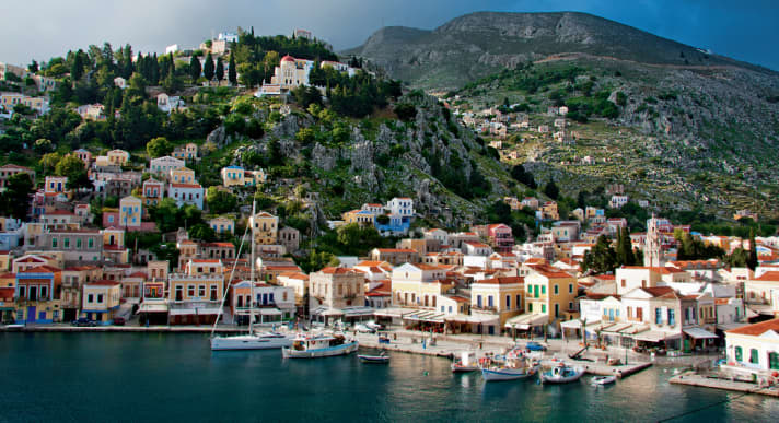 View of Symis harbour with pastel-coloured houses. The bottom is deep, a lot of chain stretching!