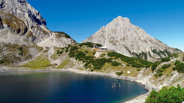 Im Morgenlicht thront die Sonnenspitze über dem Drachensee. Die Wanderer in der Coburger Hütte ­schlummern noch. ­Lange genießt das Team die grandiose ­Aussicht nicht – es ­warten noch acht Seen auf sie.