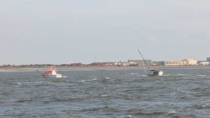 Das Rettungsboot “Otto Diersch” hat eine Leinenverbindung zum Havaristen hergestellt und zieht ihn von der Sandbank. Trotz relativ schwacher Winde um 3 Beaufort kann sich auf dem Flach eine gefährliche Welle bilden.