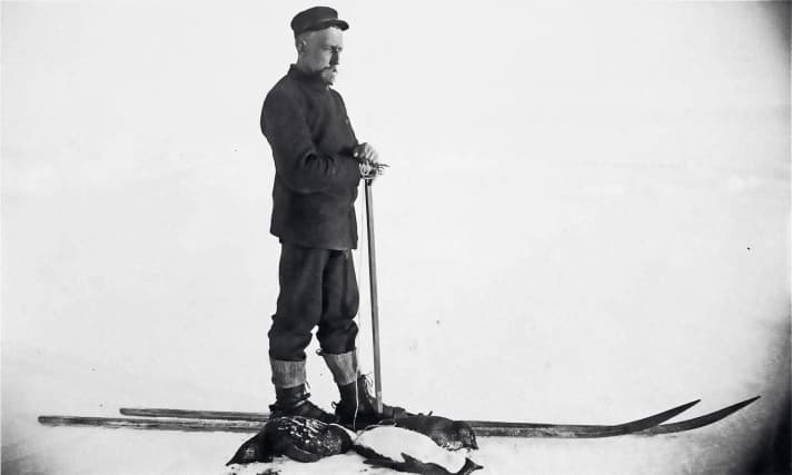 Roald Amundsen posiert auf Skiern vor seinen erlegten Pinguinen