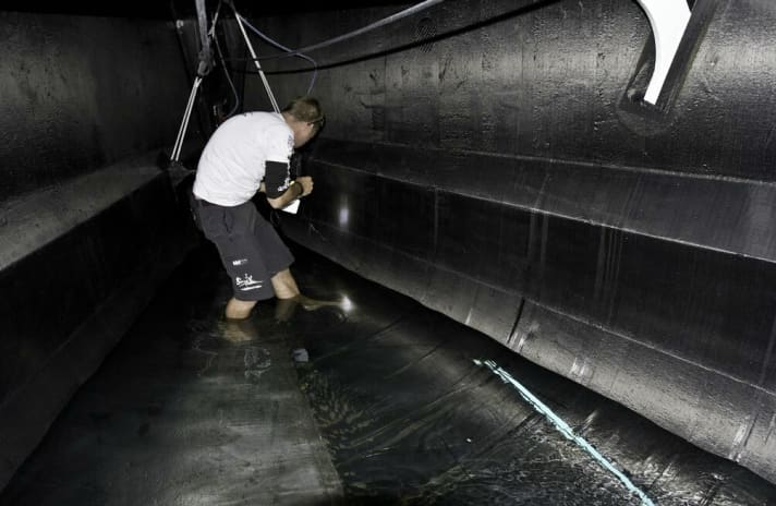   Grotta con salto: un operaio del Team Sanya è in piedi nell'acqua che entra nel ponte di prua attraverso il salto sigillato di fortuna (in basso a destra)