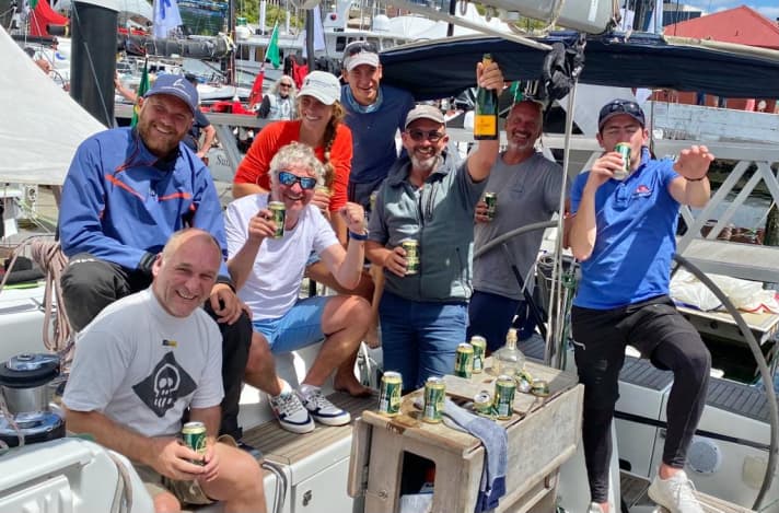 Die Berliner “Orione”-Crew ist in Hobart angekommen: Co-Skipper Axel Baumgartner hält den Champagner hoch, Bruder Peter Baumgartner steht lächelnd am Steuer