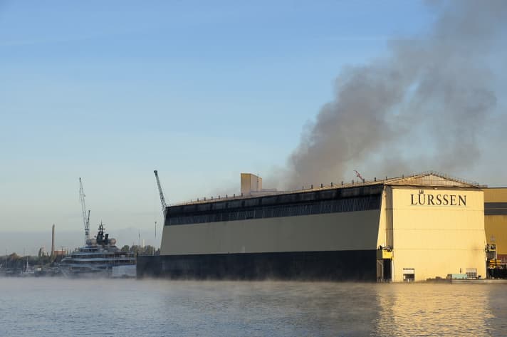 Das Großfeuer brach in der Nacht auf Freitag im 219-Meter-Schwimmdock am Lürssen-Standort Bremen-Aumund aus. Am Kai daneben liegt das kurz vor der Ablieferung stehende Projekt "Shu". | ".