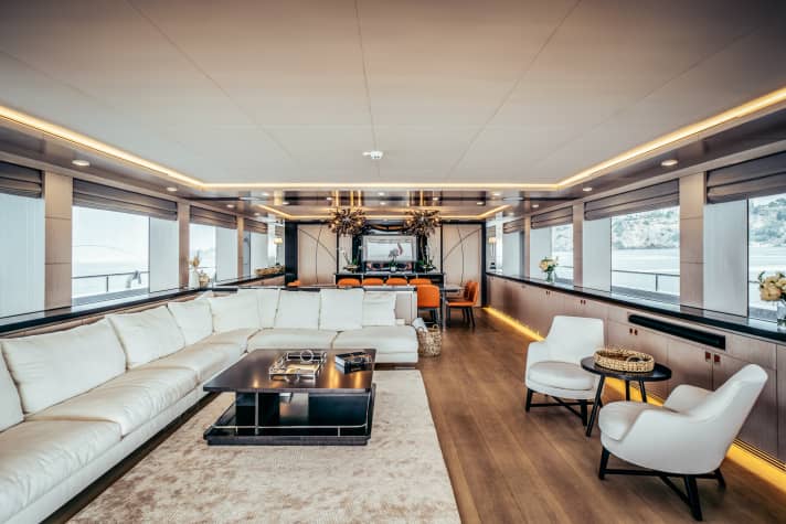 Cremefarbenes Ensemble von Flexform aus Couch und Sessel im Salon, dazu Akzente in Orange.