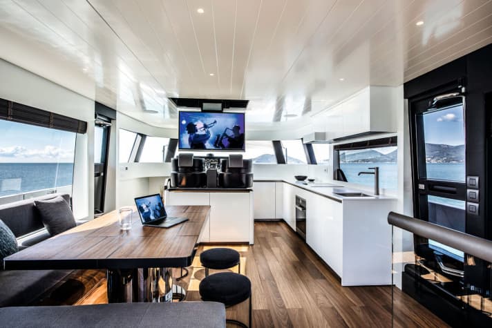Bridging the gap: The main deck combines the helm station, galley and saloon with large outdoor areas. The TV folds down behind the carbon fibre seat shells, on the port side it goes down. | n.