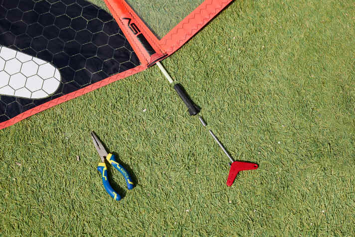 A sleeve, the batten tensioner, is attached to the batten (white) and fixed to the end of the batten pocket. The batten is extended and tensioned by screwing in the screw