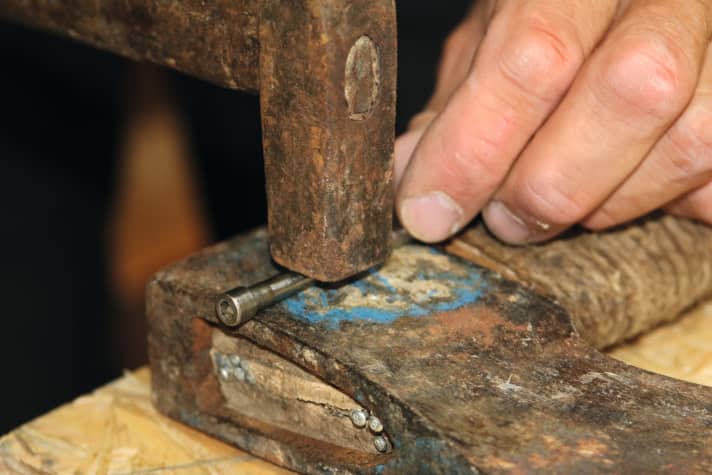Um die Metallbolzen später wieder einbauen zu können, richtet Oli diese zuerst. Setze die Schrauben in die Bolzen ein, lege diese auf eine harte Unterlage und klopfe sie mit vorsichtigen Hammerschlägen wieder gerade.