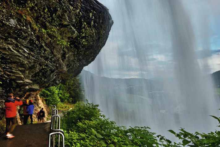 Steinsdalsfossen - una cascata a portata di mano: sul lato nord dell'Hardangerfjord, a circa due chilometri a ovest di Norheimsund, l'acqua scende a cascata fino a 50 metri di altezza. La particolarità: Un sentiero attraversa la roccia dietro la cascata e offre una prospettiva spettacolare. Norheimsund è anche il centro della scena delle barche classiche in legno. Gli ormeggi sono disponibili nel moderno porto turistico o nell'ancoraggio della grande baia.