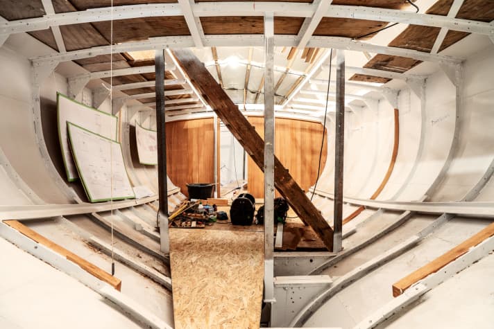 Le ketch en acier "Talisman" en phase de reconstruction : la première cloison entre le salon et le pont avant est déjà montée, l'intérieur du bateau est nu à l'exception de la coque, des membrures et des haubans.