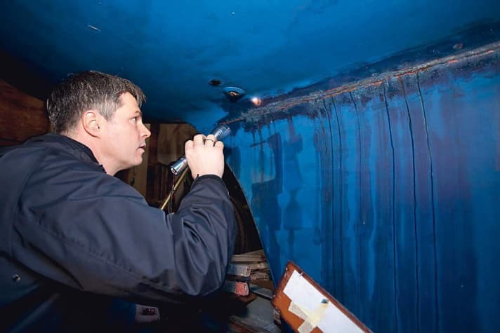 Ein Sachverständiger begutachtet einen Schaden am Rumpf und Kiel infolge einer Grundberührung