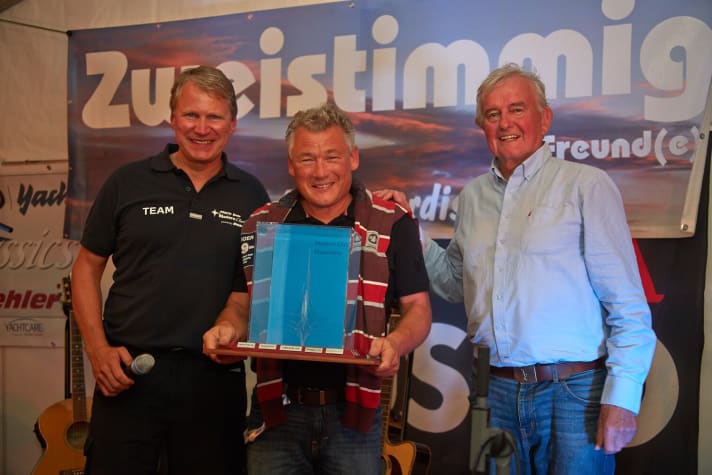   Michael Kraske, propriétaire du Senorita Helmsman "Kairos", reçoit rayonnant la "Ostseeperle" des mains du rédacteur en chef de YACHT Jochen Rieker (à g.) et du navigateur en eau bleue Bobby Schenk.