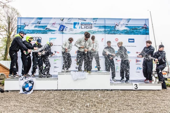   Du champagne sur le podium : les vainqueurs fêtent leur succès lors de l'ouverture de la saison de première ligue sur le lac de Starnberg