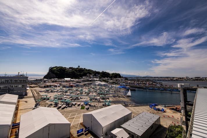  Der Olympia-Hafen von Enoshima von oben: Bei schönem Wetter eine fast paradiesische Herzschlagkammer für den olympischen Segelsport in Japan mit einem Revier, das die meisten Aktiven aufgrund schöner Wellen schätzen, aber dessen Tücken wie die schwer interpretierbare Strömung sie auch fordern. In der aktuellen Hochsommersaison muss darüber hinaus mit Flauten oder Sturmszenarien gerechnet werden…
