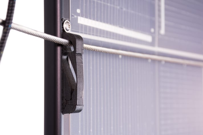   Das Paneel wird mit einem Haken auf dem Relingsdraht befestigt. Gut zu sehen ist die transparente Rückseite, dadurch können die Zellen auch mit Streulicht arbeiten