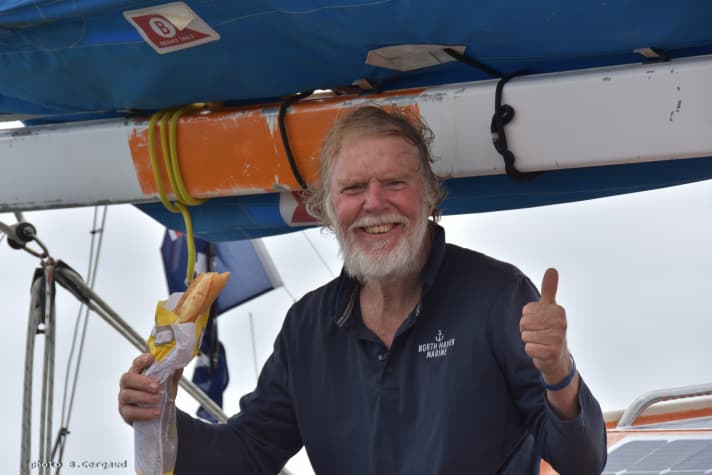   Glücklicher Skipper mit Baguette, das ihm noch auf See überreicht wurde. Dauer und Strapazen des Törns lassen sich angesichts Sinclairs Strahlen nur erahnen