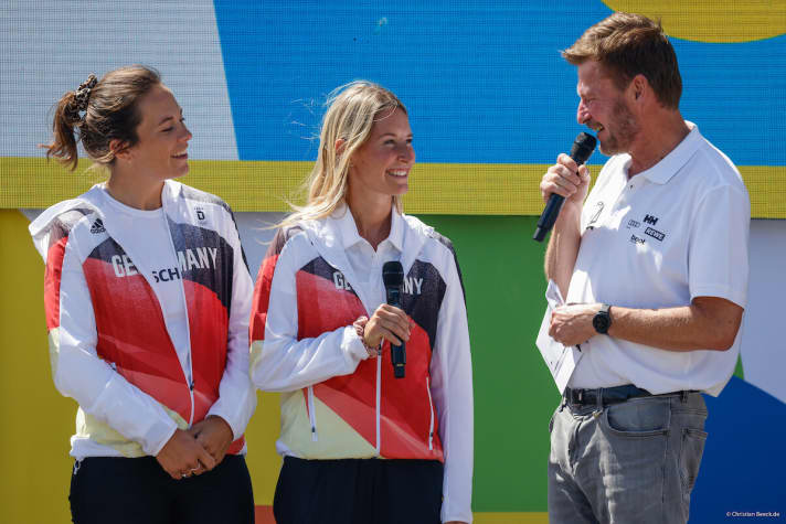   Die olympischen Silbermedaillengewinnerinnen Tina Lutz und Susann Beucke (l.) im Gespräch mit Kieler-Woche-Pressesprecher Andreas Kling. Die Skiffseglerinnen sagen bei dieser Kieler Woche als Crew nach 15 Jahren gemeinsamer Olympia-Karriere in einem Boot servus, tschüs, aber auch auf Wiedersehen. Die Sportpartnerschaft hatte mit dem Kennenlernen bei der Kieler Woche und einem ersten gemeinsamen Segelschlag am Valentinstag 2007 begonnen. Gekrönt haben die Seglerinnen aus Bayern und Norddeutschland ihren nicht immer leichten Kurs mit dem silbernen Happy End bei der Olympia-Regatta im japanischen Revier von Enoshima. Sanni Beucke ist inzwischen mit ihrer Kampagne "This race is female" ins Offshore-Fach gewechselt, Tina Lutz bleibt dem Segelsport als Bundesliga-Seglerin, Trainerin und vielleicht auch in weiteren Bereichen treu