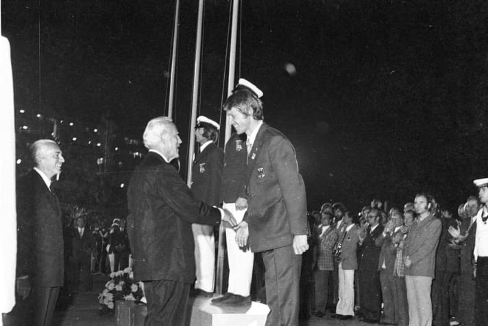 Sul piazzale del porto di Schilksee, il timoniere FD Ulli Libor riceve la medaglia di bronzo nel 1972. A sinistra Beppe Croce, allora presidente della Federazione Mondiale della Vela.