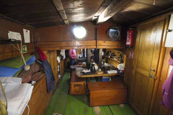 Blick von achtern in den ehemaligen Frachtraum, wo man zünftig auf Seekisten sitzt