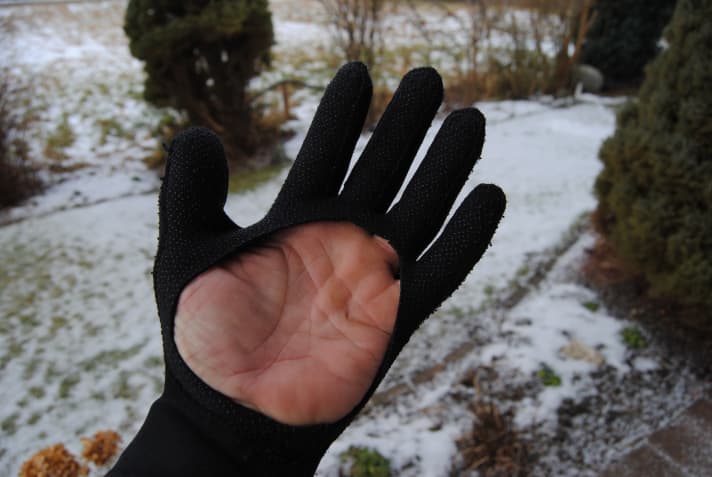 Mit der Schere schneidet Woife die Handflächen der Fingerhandschuhe aus, um später besser greifen zu können