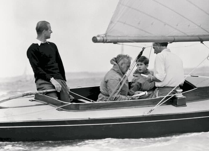 Uffa Fox (2nd from left) with Prince Philip (at the tiller) and Prince Charles (2nd from right)