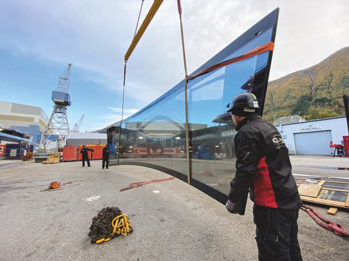 Diffizile Montage: Im Kran hängt die 11,20 Meter lange und gebogene Frontscheibe für die Observation-Lounge von „REV Ocean” auf Deck neun. Sie wiegt stattliche 4,5 Tonnen. | n.
