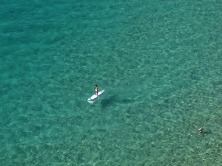 Elaborate photoshoot above the natural swimming pool in Corsica (Algajola). The paraglider from which the photo was taken offers an even better view than on the SUP board.