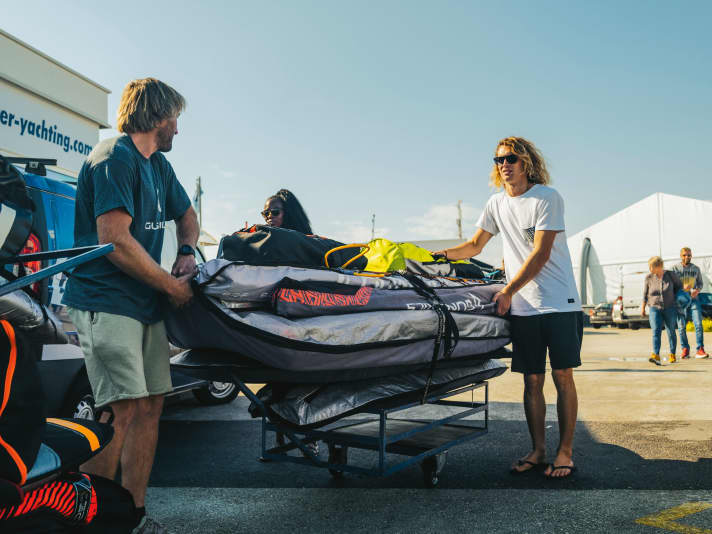 Wagen für Wagen, entlang des schmalen Docks. Vollgepackt mit Surfmaterial in Richtung Schiff.