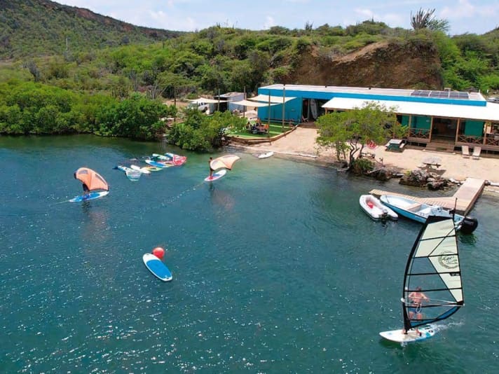 Durch die Tiefe auch sehr schön zum Foilen: Karibik-Feeling mit entspanntem Surf-Vibe machen bei Windsurfing Curaçao den böigen Wind wieder wett.