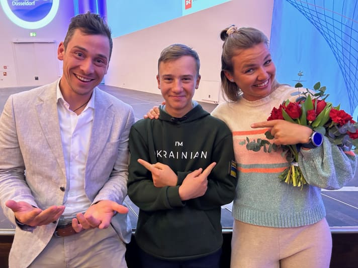 Sviatoslav Madonich ist 15 Jahre alt und wird 2023 seine letzte Opti-WM mit Medaillenchancen bestreiten, bevor er in eine neue Klasse umsteigt. Auf der boot warben halb ernst und halb im Spaß die 470er-WM-Sechste Anastasiya Winkel und der zweimalige olympische 49er-Bronzemedaillengewinner Thomas Plößel beim angehenden Umsteiger für ihre Disziplinen