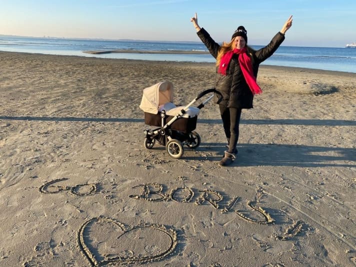   Birte Herrmann con la figlia Marie-Louise sulla spiaggia del Mar Baltico a Kiel durante una passeggiata d'Avvento. Al marito Boris Herrmann manda un grande cuore e una valigia di Natale piena di sensazioni di casa nel Pacifico del Sud.