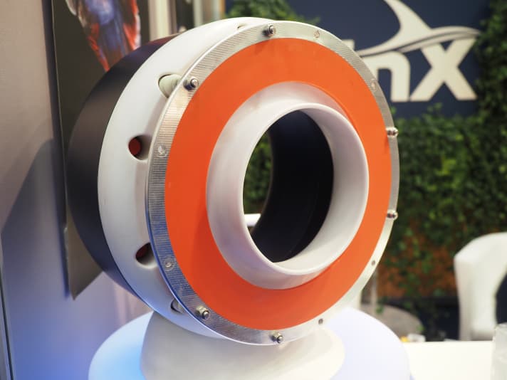   The orange rubber membrane pulses back and forth, creating pressure waves that travel over the white nozzle and pull water backwards from inside the ring