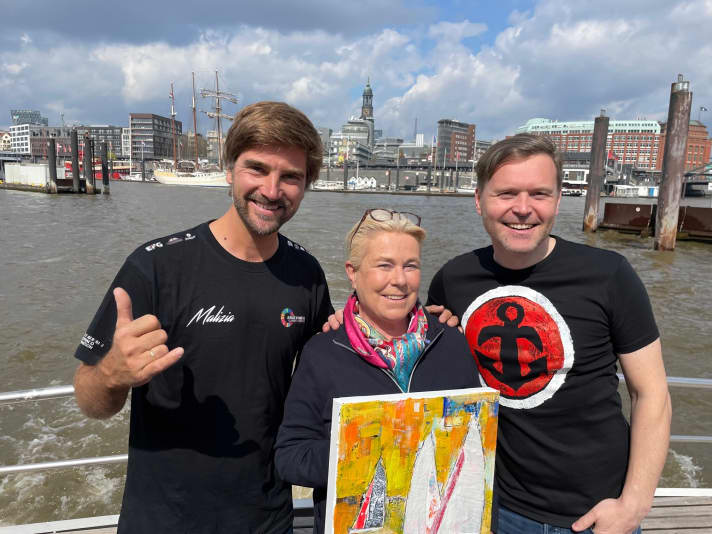   Lors d'une promenade printanière en barque sur l'Elbe avec des amis : Hubert Neubacher (Barkassen-Meyer), l'artiste Heinke Böhnert et Boris Herrmann. Neubacher, "l'inventeur des barques artistiques" et fan d'Herrmann, avait invité à cette sortie sur l'Elbe. Heinke Böhnert lui a offert un tableau en guise de remerciement, en souvenir de la période passionnante du Vendée Globe et comme avant-goût des sommets à venir.