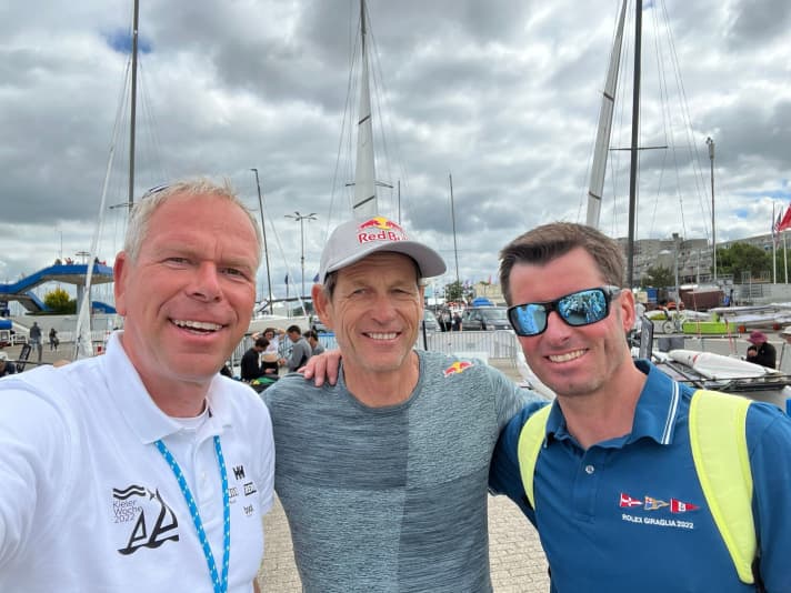   Waiting instead of sailing: Nacra 17 Olympic champion Santi Lange from Argentina used the time to meet friends and organisers. The picture shows Kieler Woche sports director Dirk Ramhorst (l.) and former Olympic participant Johannes Polgar, who still knows Lange from their Tornado days. Lange was delighted with the organisation of Kieler Woche and its performance and signalled his support for a possible comeback of Kieler Woche in the Olympic World Cup events