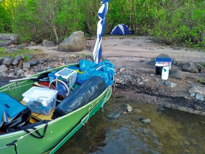   Das voll beladene Boot am Ufer einer kleinen Insel. Lenz übernachtet zwischen Büschen im Biwakzelt