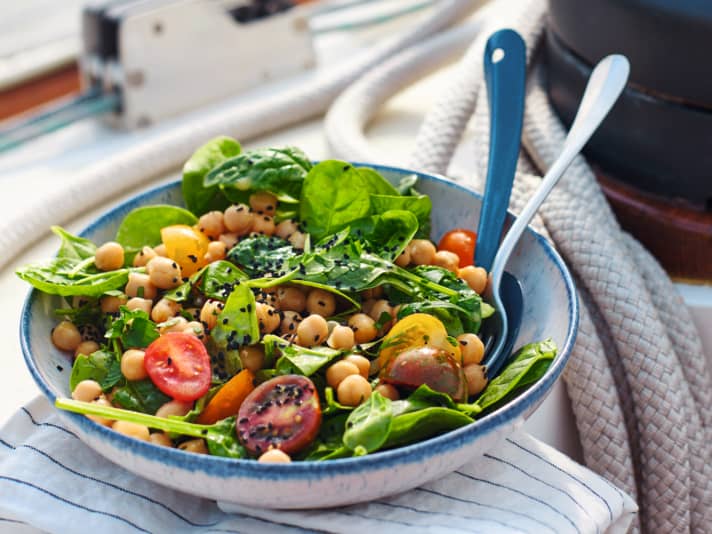 Cooking on board Chickpea salad with tomatoes, spinach and black cumin