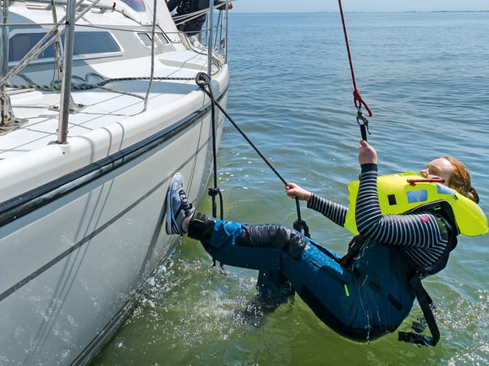 If a rescue via the stern is too dangerous, try to climb back on board amidships, for example with the help of a rescue ladder. If the casualty is exhausted or the swell is too heavy, he must be winched up. To do this, attach the spi halyard to the lift strap on the waistcoat