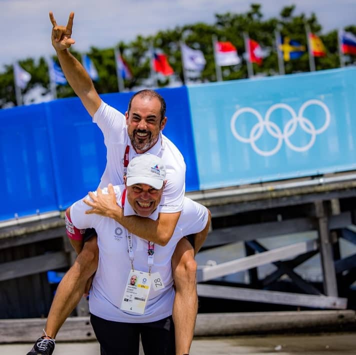   Jesus Renedo porta Pedro Martinez sulle spalle: I due spagnoli formano un dinamico duo di fotografi, caratterizzano lo sport della regata internazionale con le loro prospettive personali ai suoi vertici e riescono a non perdere mai la loro energia positiva anche nelle circostanze più avverse: il Sailing Energy