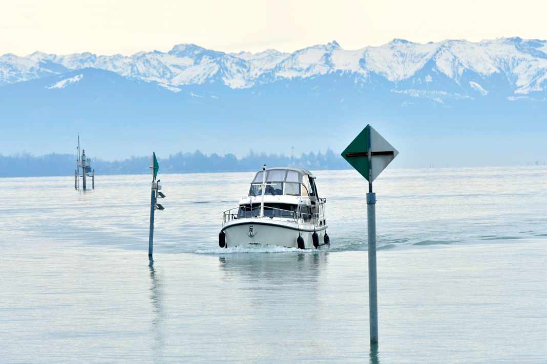 Die schneebedeckten Allgäuer Alpen im Hintergrund: Unser Charterboot läuft in den Hafen von Friedrichshafen ein