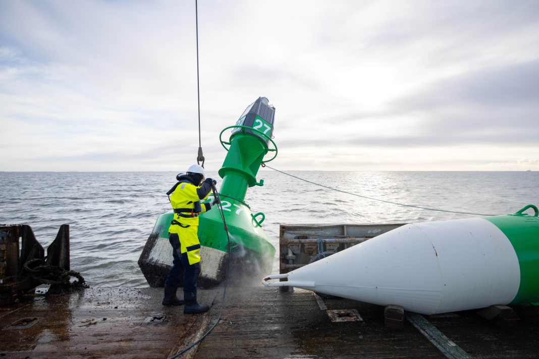 Ab in die Winterpause: Auf einem Tonnenleger wird eine große Fahrwassertonne der Sommerbetonnung gereinigt, bevor sie an Bord geholt wird. Rechts daneben liegt die Wintertonne bereit.