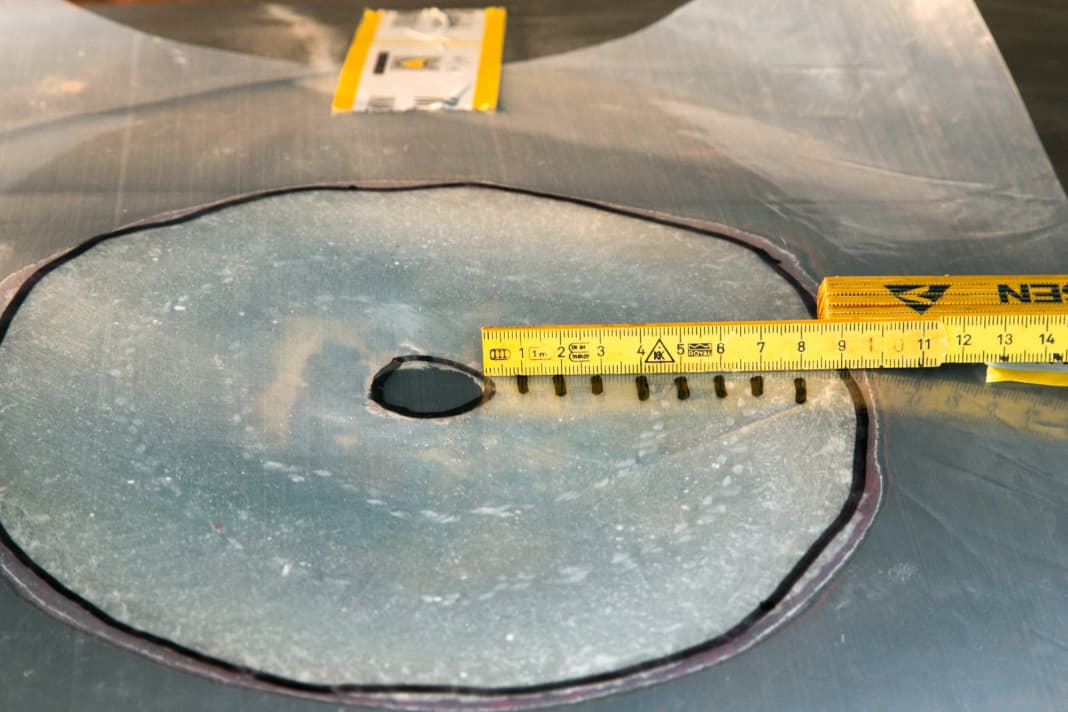 Sand the stock: Sand a stock twelve times the thickness of the laminate around the hole, in this case about ten centimetres. Transfer the outline to a sheet of foil and mark the size of the fibreglass patches on it